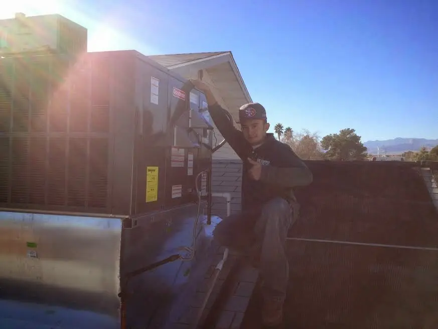 HVAC technician performing Heat Pump Repair on a rooftop unit in Spanaway