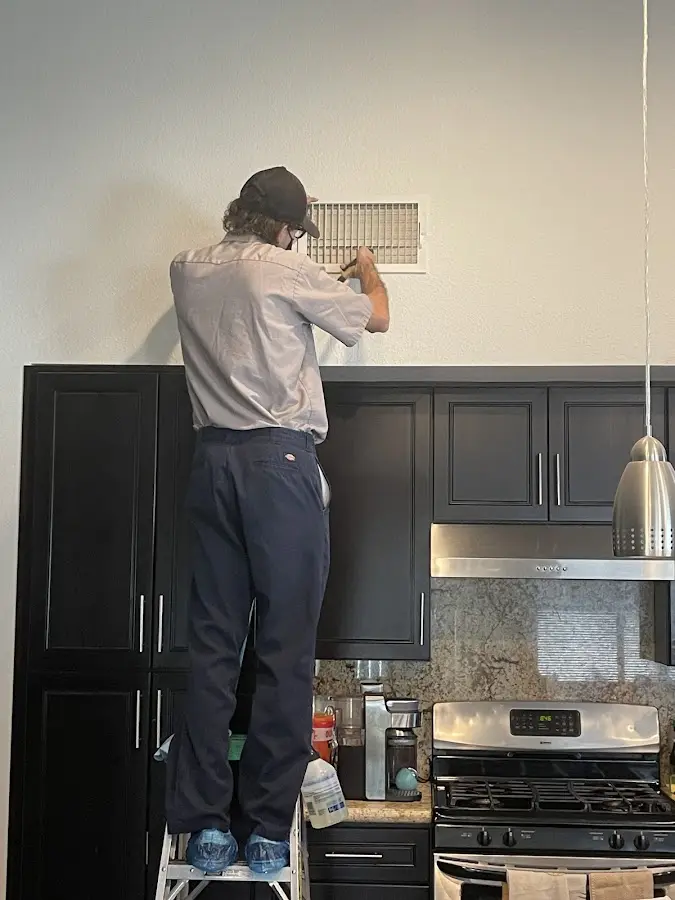 Technician inspecting an air vent during HVAC service in Spanaway